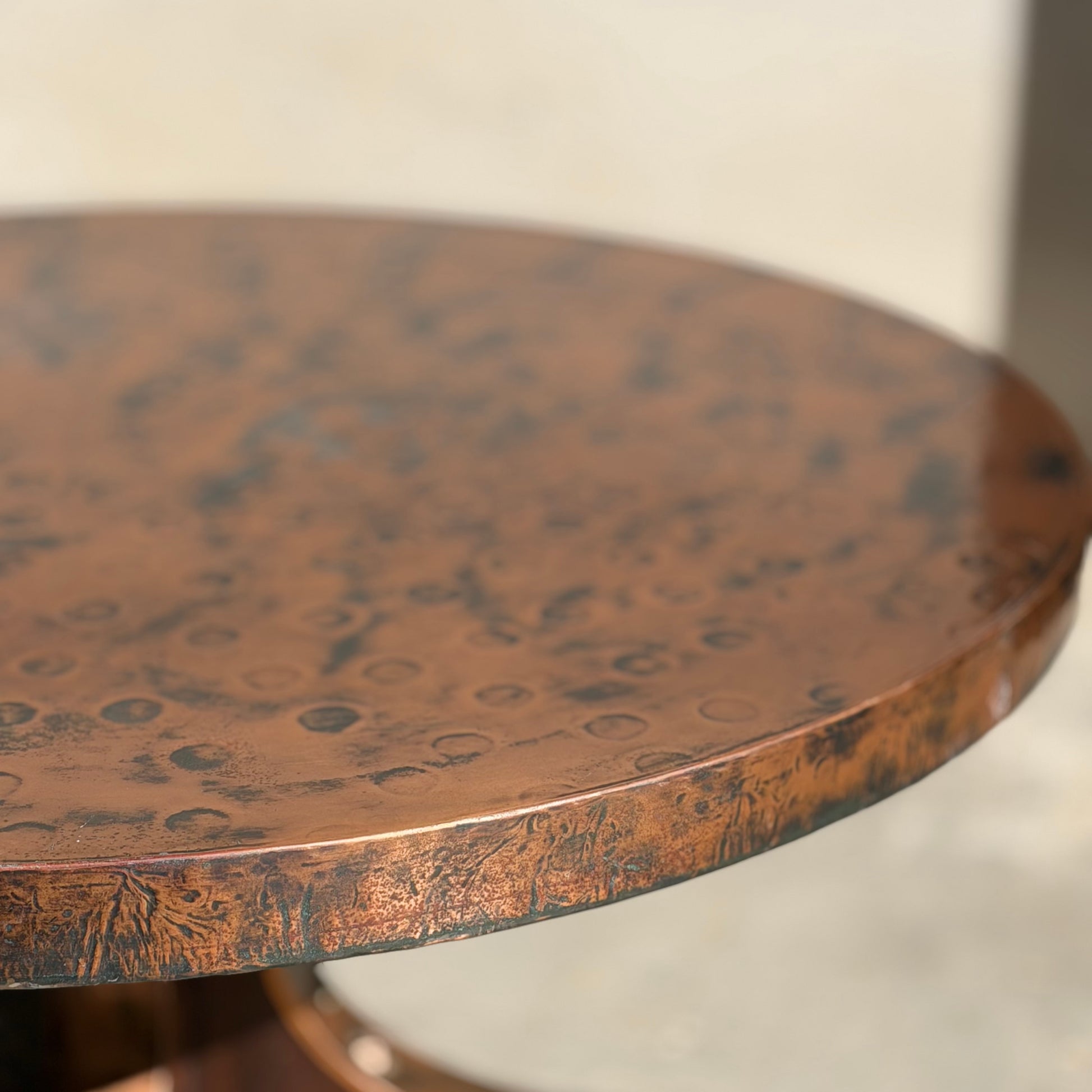 A close-up of the Vintage Louis Berczi Hammered Copper Round Coffee Table – Rare Australian Collectible (Revive), showcasing its hand-hammered, textured copper surface with circular and mottled patterns. The background is softly blurred.