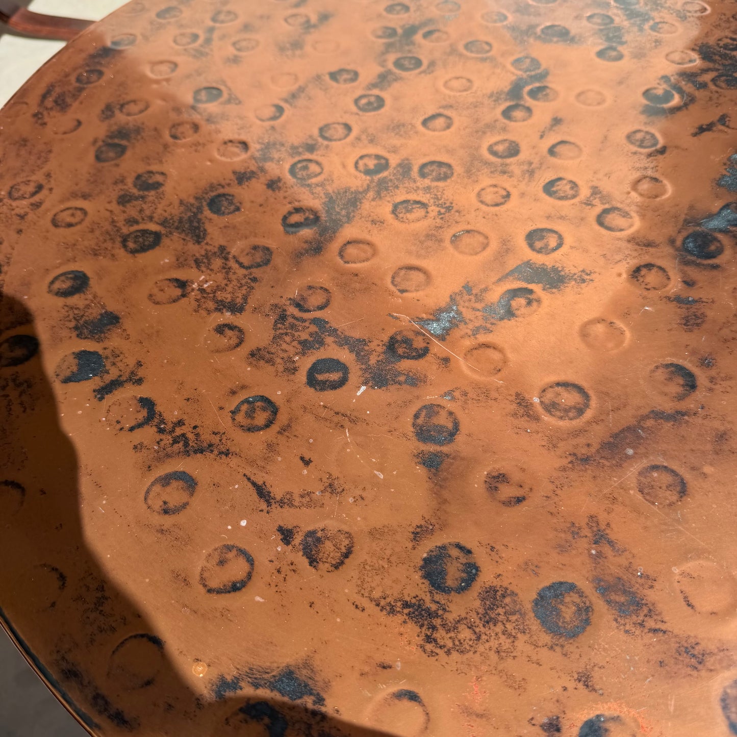 A close-up of the Vintage Louis Berczi Hammered Copper Round Coffee Table, a rare Australian collectible from Revive, featuring hand-hammered circular indentations, dark spots, and aged patina—ideal for vintage decor.