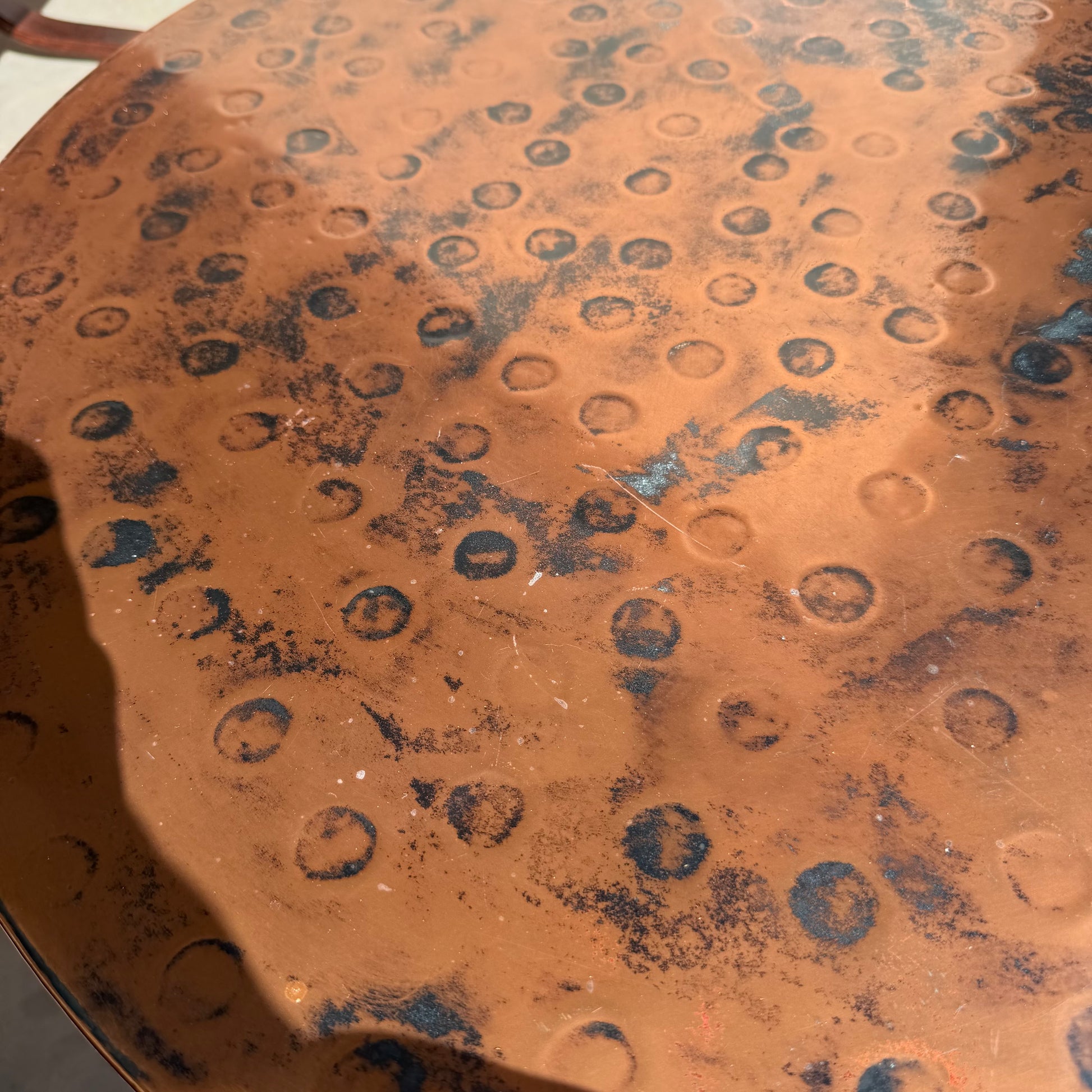 A close-up of the Vintage Louis Berczi Hammered Copper Round Coffee Table, a rare Australian collectible from Revive, featuring hand-hammered circular indentations, dark spots, and aged patina—ideal for vintage decor.