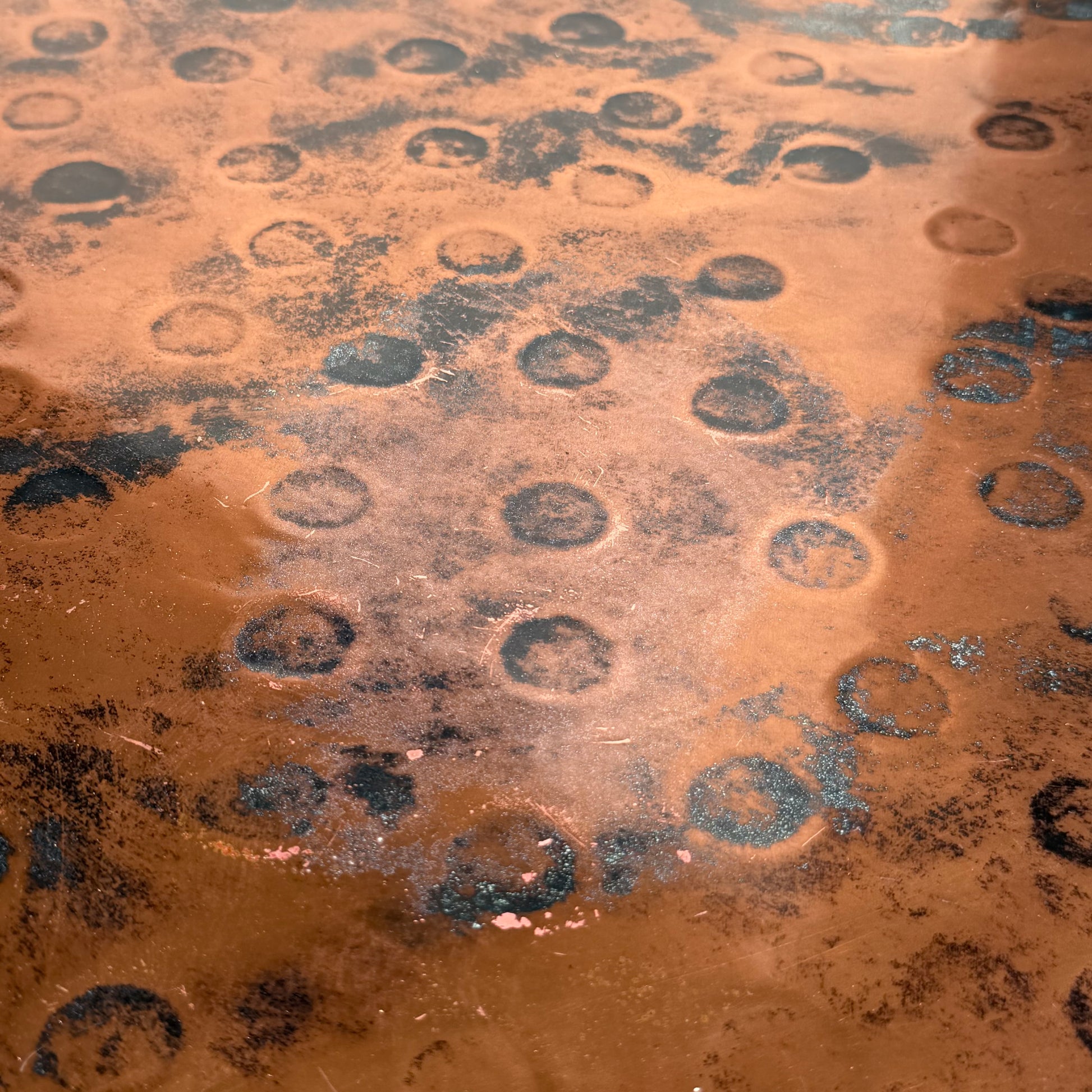 A close-up of the Vintage Louis Berczi Hammered Copper Round Coffee Table highlights its weathered, textured surface with dark circular marks, showcasing the unique character of this rare Australian collectible.