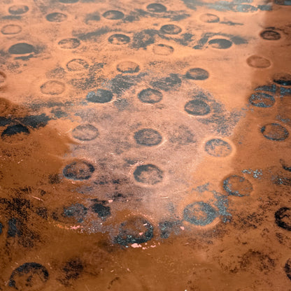A close-up of the Vintage Louis Berczi Hammered Copper Round Coffee Table highlights its weathered, textured surface with dark circular marks, showcasing the unique character of this rare Australian collectible.