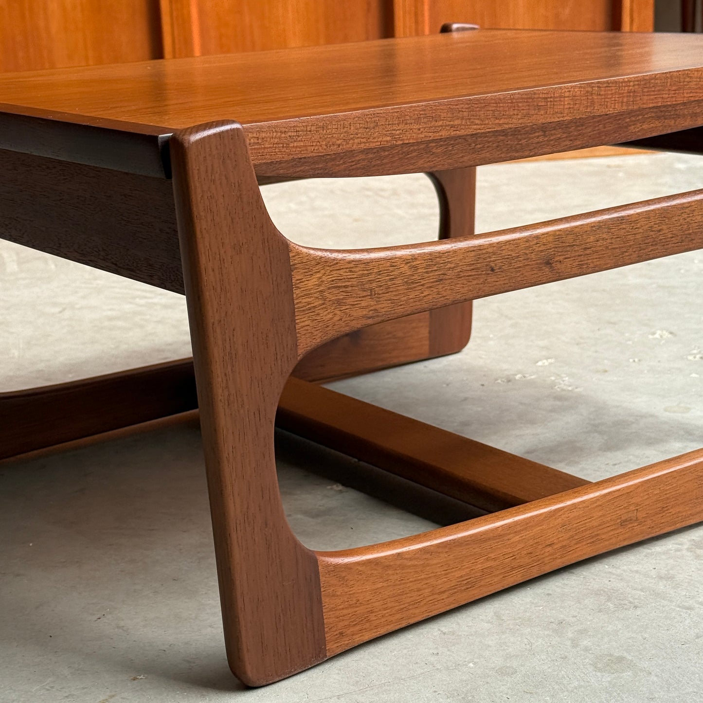 Close-up of the ultra rare Gerald Easden Coffee Table in Blackwood with sleigh leg base (Rediscover), set on a concrete floor against a wooden-paneled wall—a striking example of Australian vintage design.