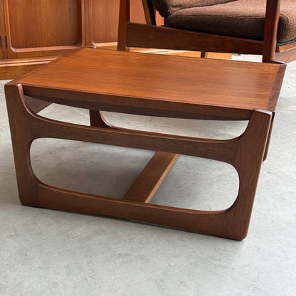 An ultra rare Gerald Easden coffee table in Blackwood with a sleigh leg base (Rediscover) sits on a concrete floor, showcasing mid-century style. A brown upholstered chair is partially visible behind this unique piece of Australian vintage furniture.