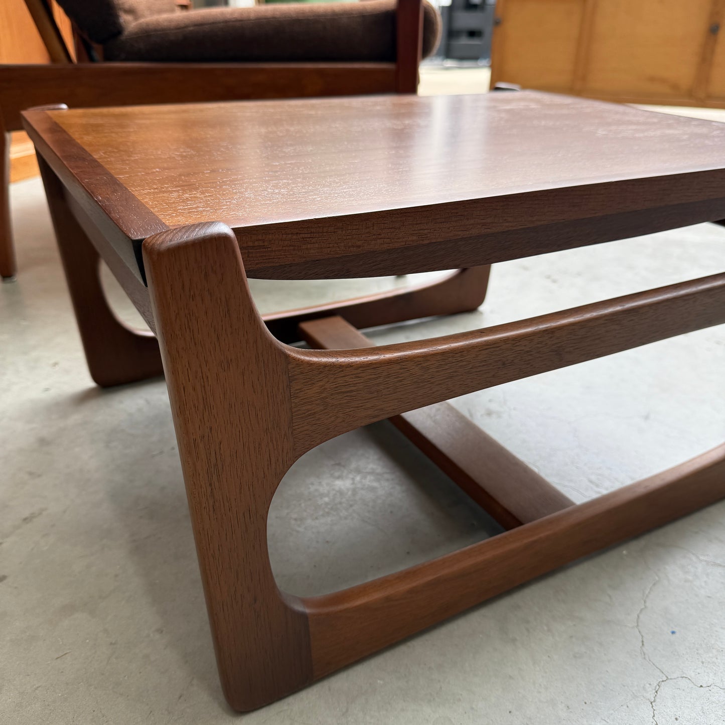 A close-up of the ultra rare Gerald Easden Coffee Table in Blackwood with a sleigh leg base (Rediscover) is shown on a light concrete floor, with matching Australian vintage furniture visible in the background.