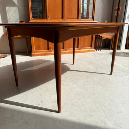 A Fully Restored Parker No.92 D End Dining Table (Rediscover) with tapered legs stands on a concrete floor in a sunlit room, while a wooden cabinet and nesting tables highlight vintage Australian furniture style in the background.