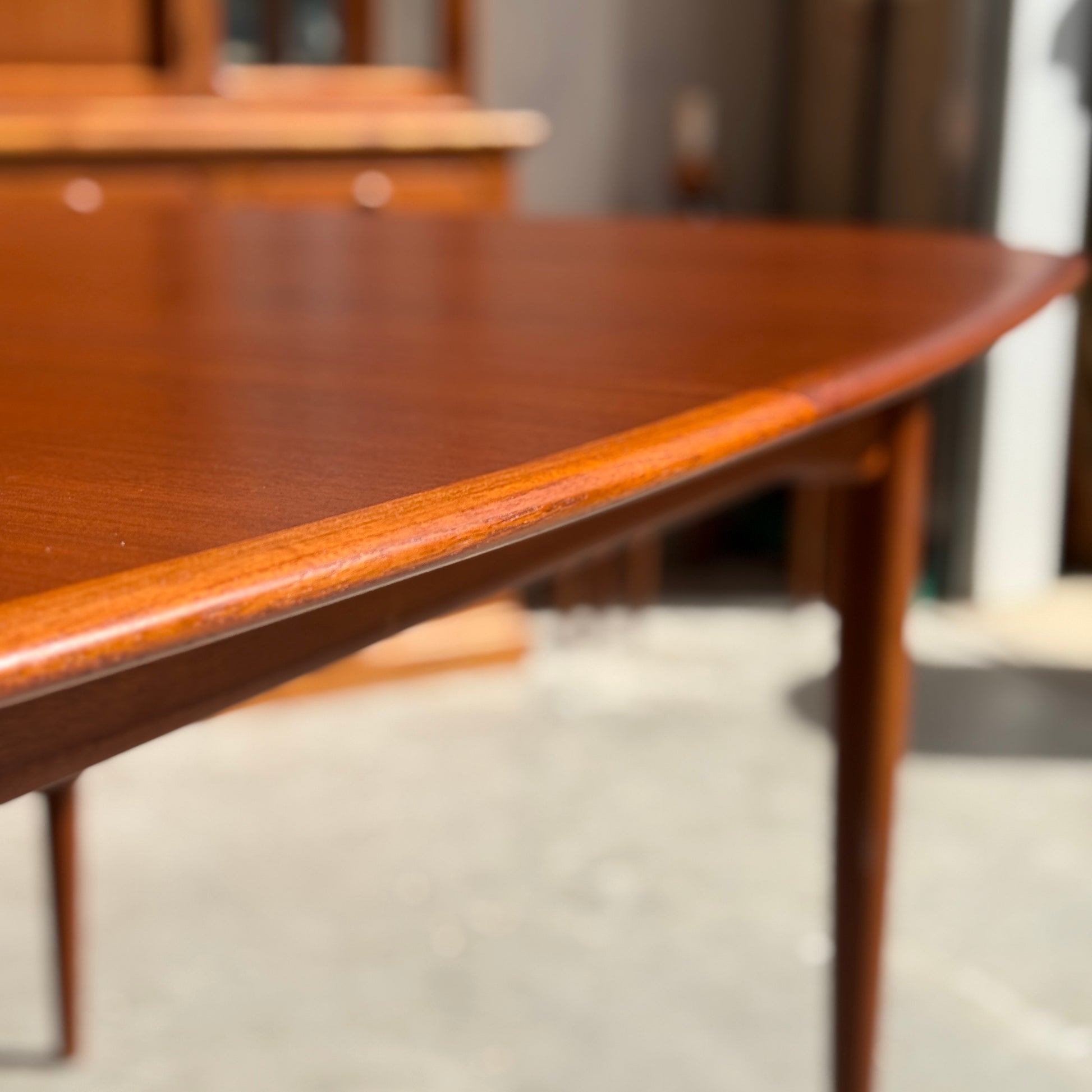 Close-up of a fully restored Parker No.92 D End Dining Table (Rediscover) with rounded edges and slender legs, set in a sunlit room with blurred vintage Australian furniture in the background.