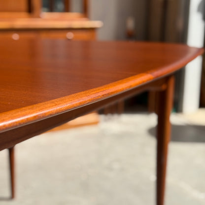Close-up of a fully restored Parker No.92 D End Dining Table (Rediscover) with rounded edges and slender legs, set in a sunlit room with blurred vintage Australian furniture in the background.