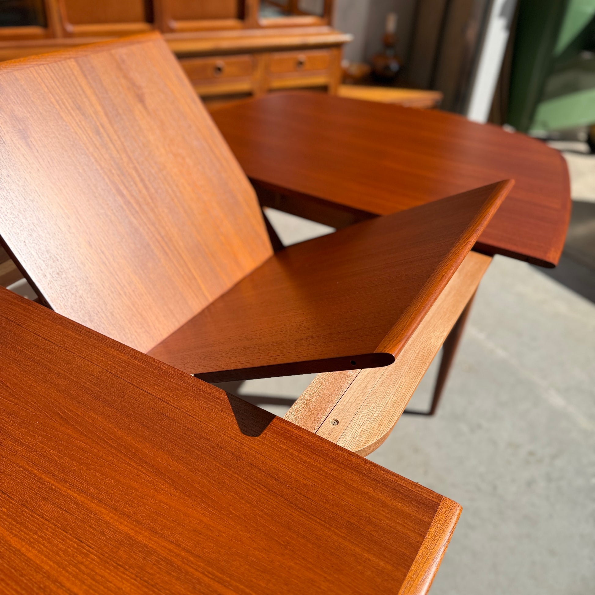 Fully restored Parker No.92 D End Dining Table (Rediscover) with extending leaves and a rich finish, sunlit on a gray floor, paired with vintage Australian furniture in the background.