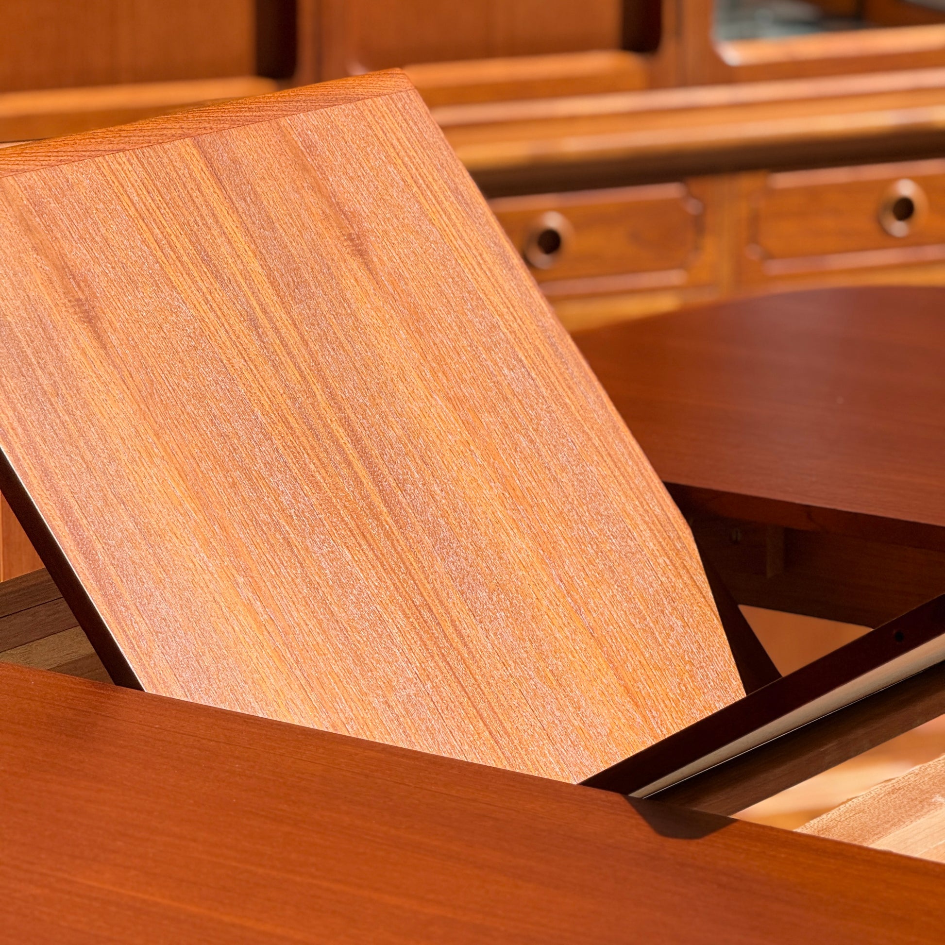 Close-up of the Fully Restored Parker No.92 D End Dining Table (Rediscover) with its extension leaf being added, surrounded by matching mid-century modern wooden furniture in a warm, classic vintage Australian finish.