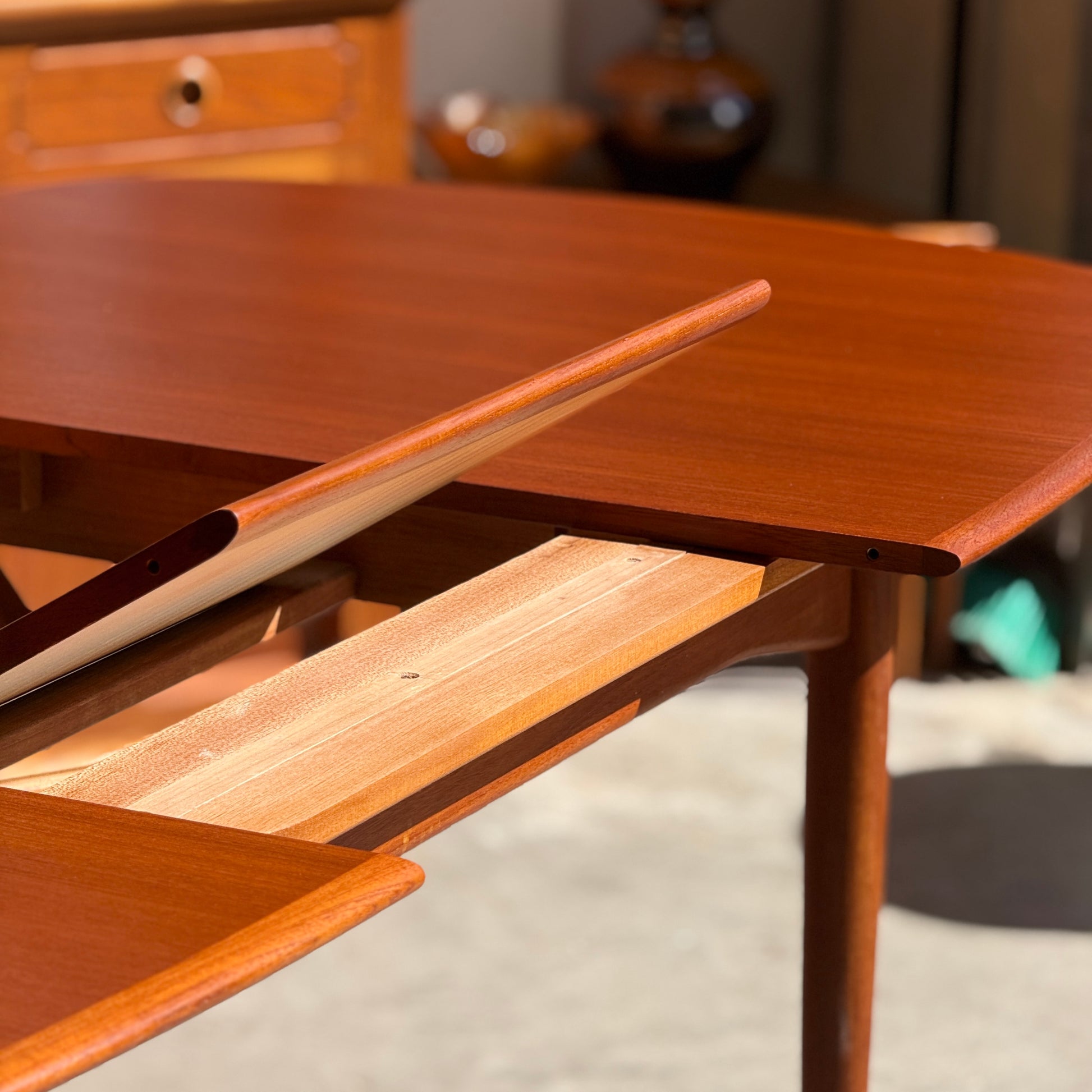 A close-up of a Fully Restored Parker No.92 D End Dining Table (Rediscover) with an extra leaf partially inserted, showcasing its smooth polished surfaces and warm wood tones in sunlight—a stunning vintage Australian piece.