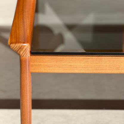 Close-up of the Tessa TC 21 Coffee Table Frame Restored (Revive) with a glass top, highlighting smooth joinery, natural wood grain, and modern minimalist craftsmanship as sunlight casts shadows below.