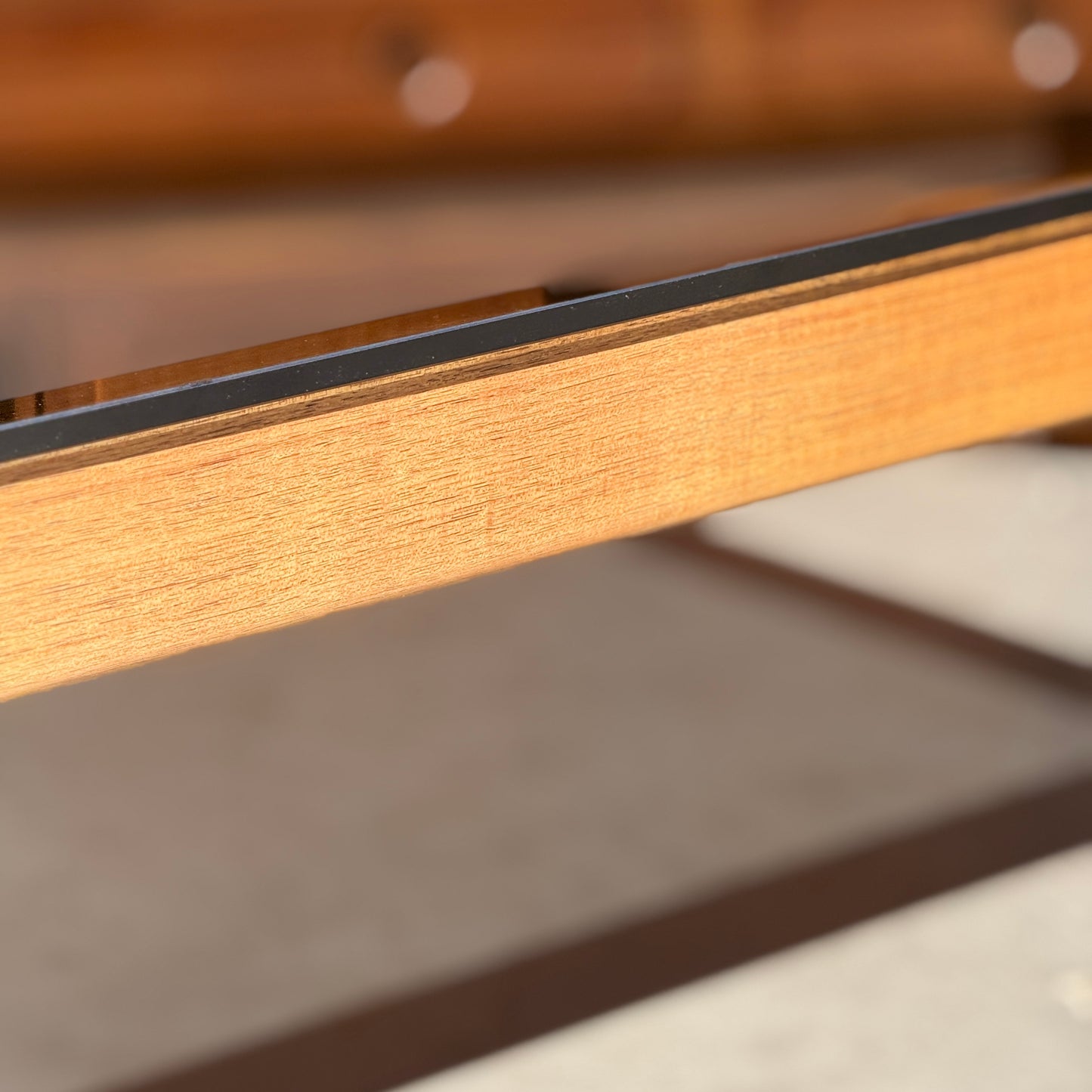 Close-up of the restored Tessa TC 21 Coffee Table Frame - (Revive) with a metal edge, highlighted in warm sunlight and a blurred backdrop—showcasing its modern minimalist design.