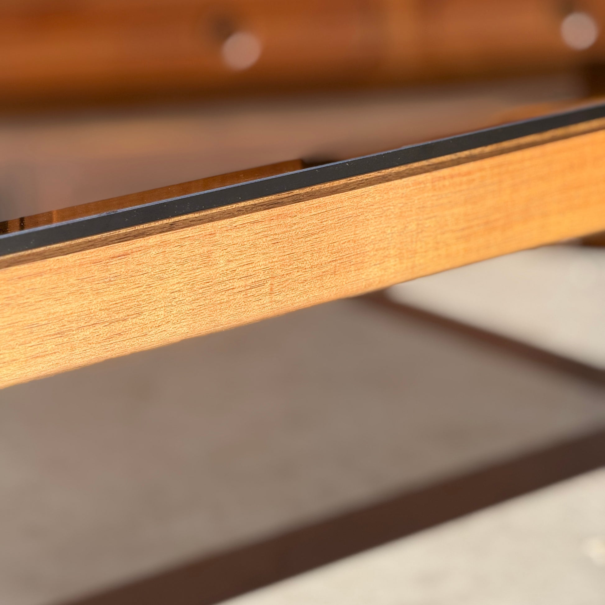 Close-up of the restored Tessa TC 21 Coffee Table Frame - (Revive) with a metal edge, highlighted in warm sunlight and a blurred backdrop—showcasing its modern minimalist design.