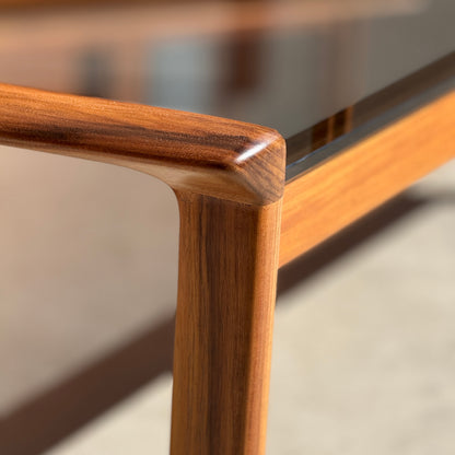 Close-up of the Tessa TC 21 Coffee Table Frame Restored - (Revive) corner, showcasing its sleek rounded edge, glass top, and warm natural wood grain for a modern minimalist look and smooth craftsmanship.