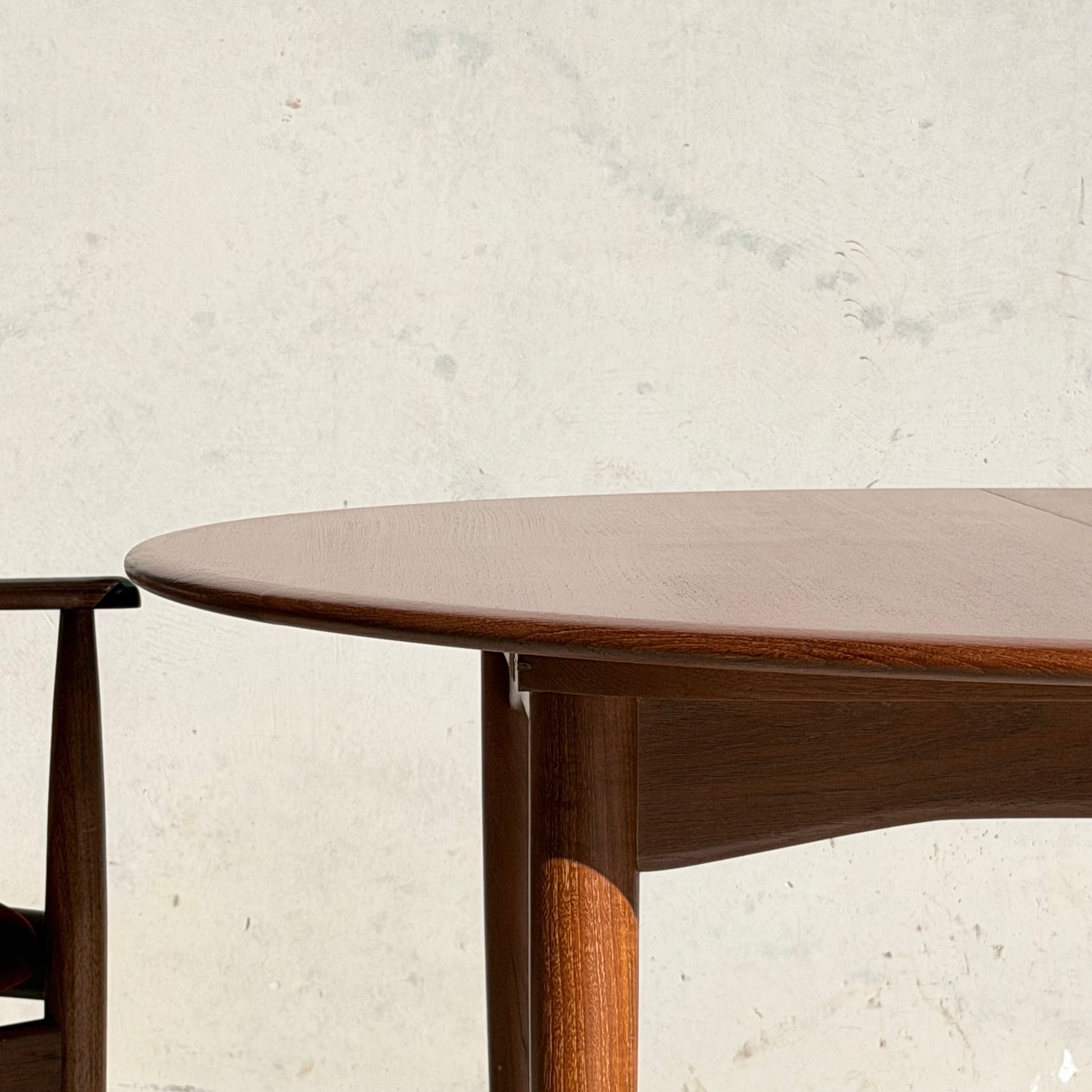 Close-up of the Fully Restored Parker 90 Round Extension Butterfly Table Only (Rediscover), featuring rounded edges against a light, textured wall. Natural light emphasizes its mid-century modern design in this minimal, inviting scene.
