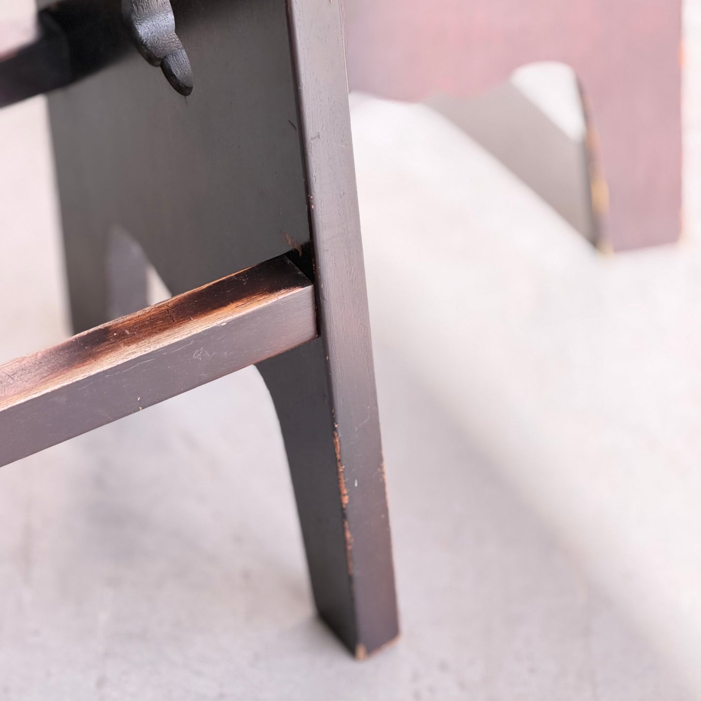 Close-up of the lower legs of a dark wooden stool on a light floor, showing worn edges and scratches—classic character seen in 1970s Australian Mid-Century Modern Spanish Revival Davis Stools – Set of 3 (Revive).
