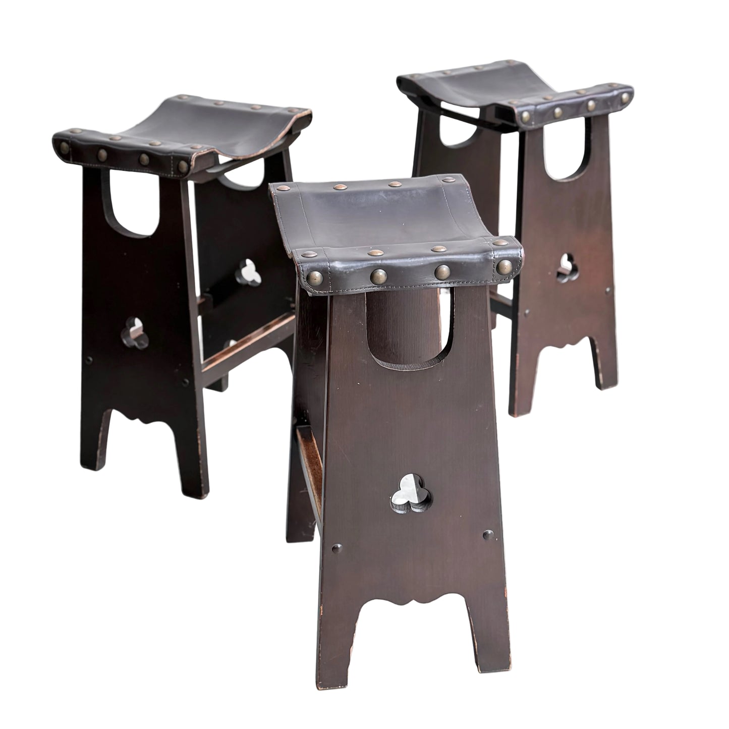 A set of three 1970s Australian Mid-Century Modern Spanish Revival Davis Stools (Revive) are arranged on a light concrete floor against a plain wall.