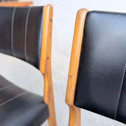 Two Vintage TH Brown Blackwood Dining Chairs (from a set of 4) with black leather seats and backs are shown side by side, focusing on the rich wood texture and fine leather upholstery of these elegant Revive dining chairs.