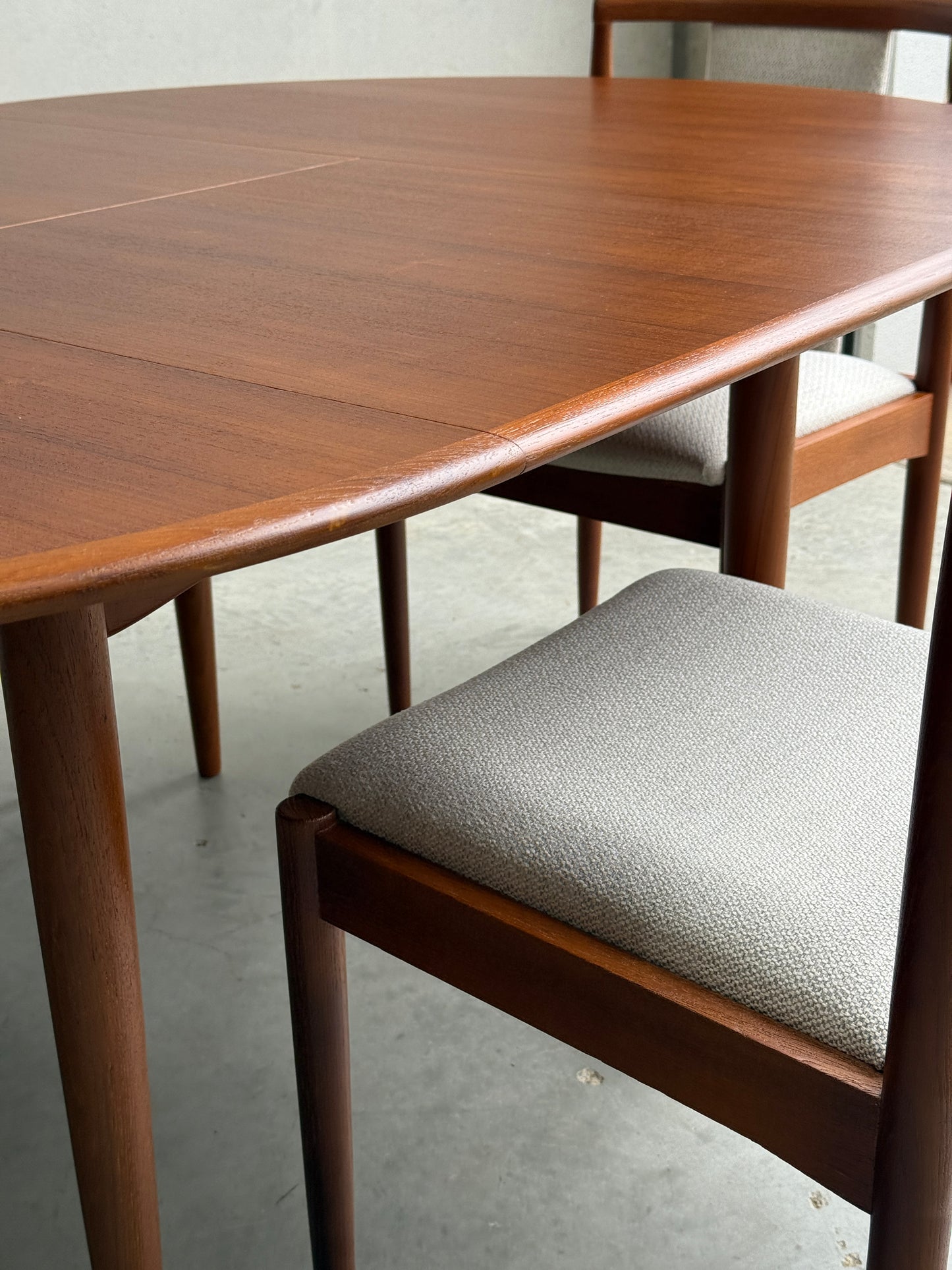 A close-up of the Fully Restored Parker 90 Round Extension Butterfly Table Only (Rediscover), showcasing its rounded edges and mid-century modern design on a concrete floor.