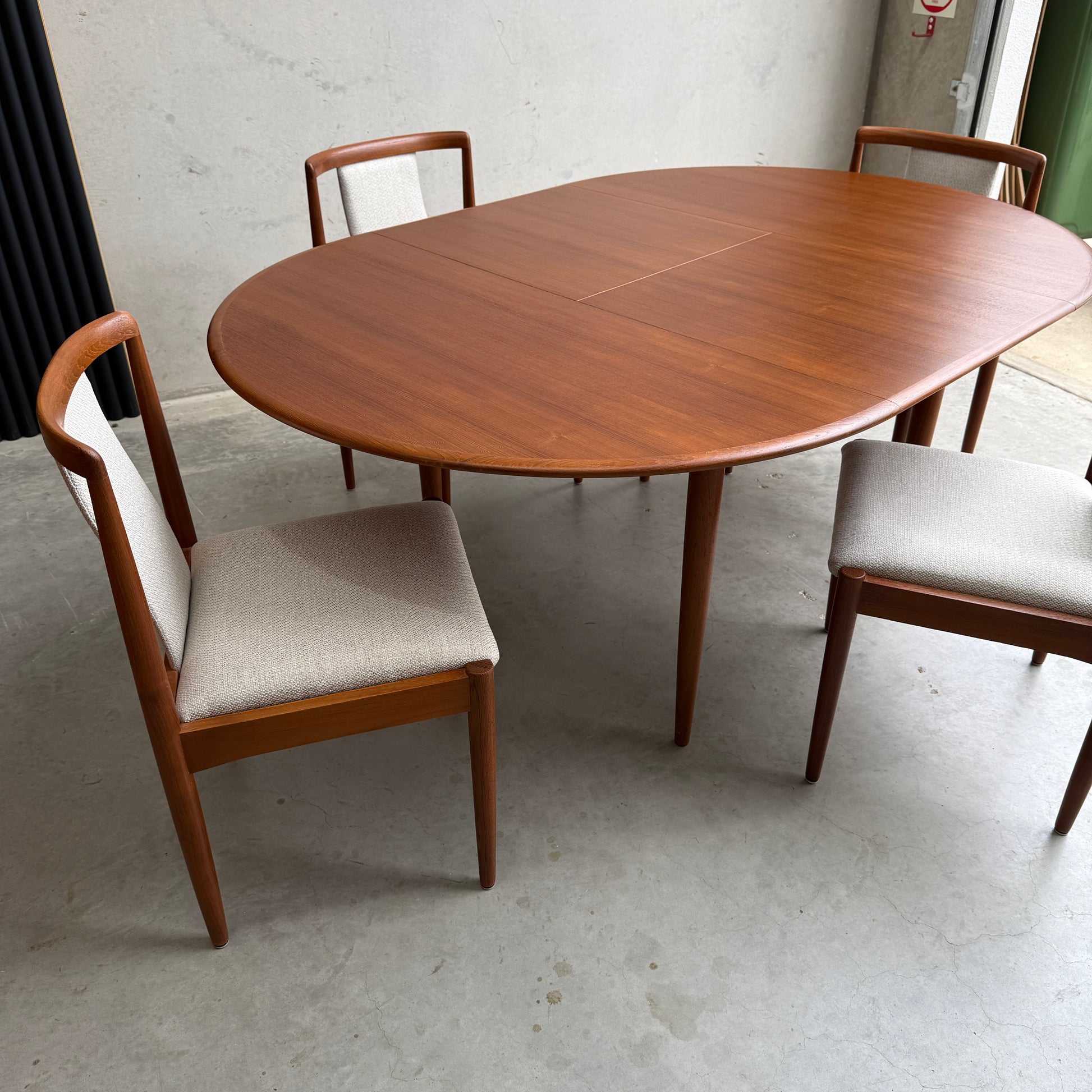 A fully restored Parker 90 Round Extension Butterfly Table (Rediscover) sits on a light-colored concrete floor next to a plain wall.
