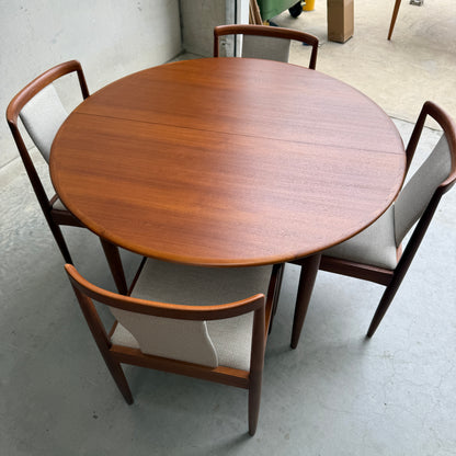 The Fully Restored Parker 90 Round Extension Butterfly Table Only (Rediscover) stands on a concrete floor in a minimalist indoor space, highlighting timeless mid-century modern style.