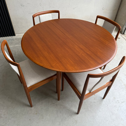 A Fully Restored Parker 90 Round Extension Butterfly Table (Rediscover) set on a concrete floor in a minimalist space brings timeless mid-century modern elegance to your dining area.
