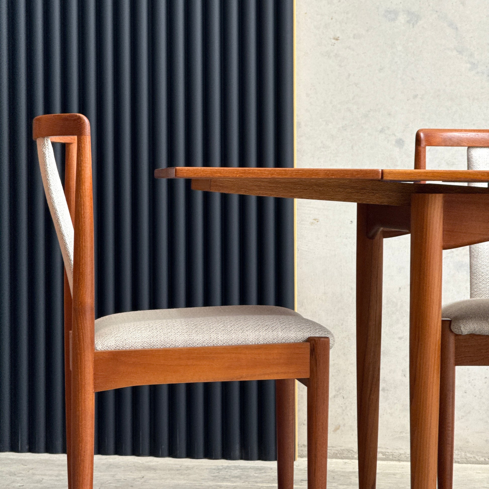 The Fully Restored Parker Dining Suite 5 Piece Square - Number 140 (Rediscover) sits on a concrete floor, set against a dark vertical slatted wall and a light-colored textured wall.