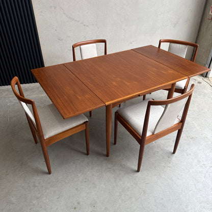 A Fully Restored Parker 140 Square Extension Table (Rediscover), with two leaves and four matching chairs with light upholstered seats, sits on a light concrete floor against a plain wall for a clean, timeless look.