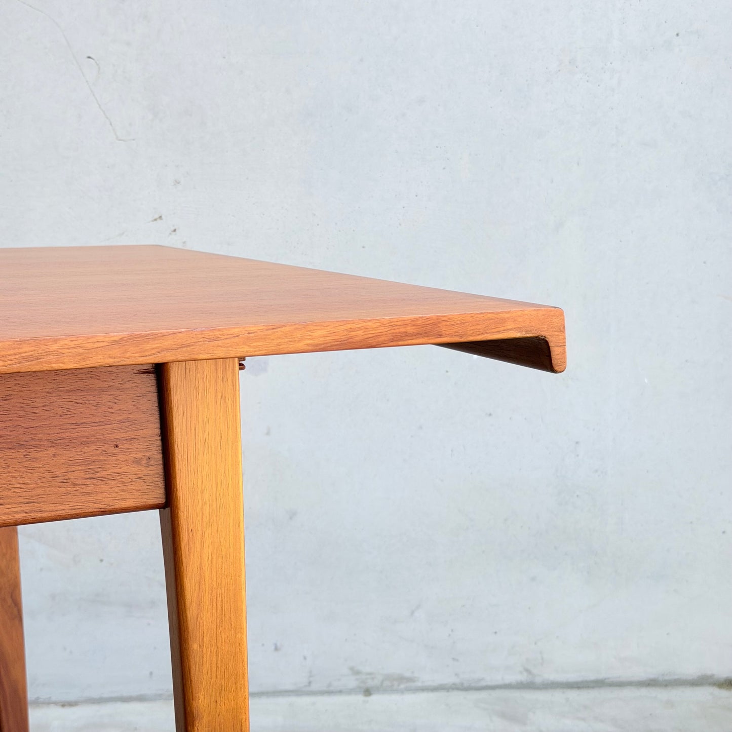 A close-up of the Rare Gerald Easden Rectangular Extension Dining Table (Rediscover) showcasing its mid-century modern design with clean lines and minimalist style, set against a plain, light-colored wall.