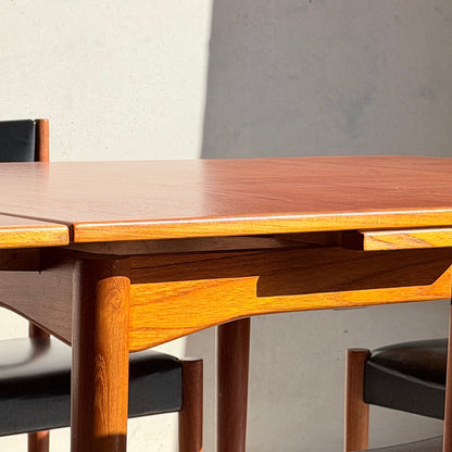 A close-up of the Vintage Parker Dining Suite 5 Piece Square - Number 140, featuring a wooden table with rounded legs and two matching chairs in black frames, all set in sunlight against a pale wall—Scandinavian-inspired Australian design.