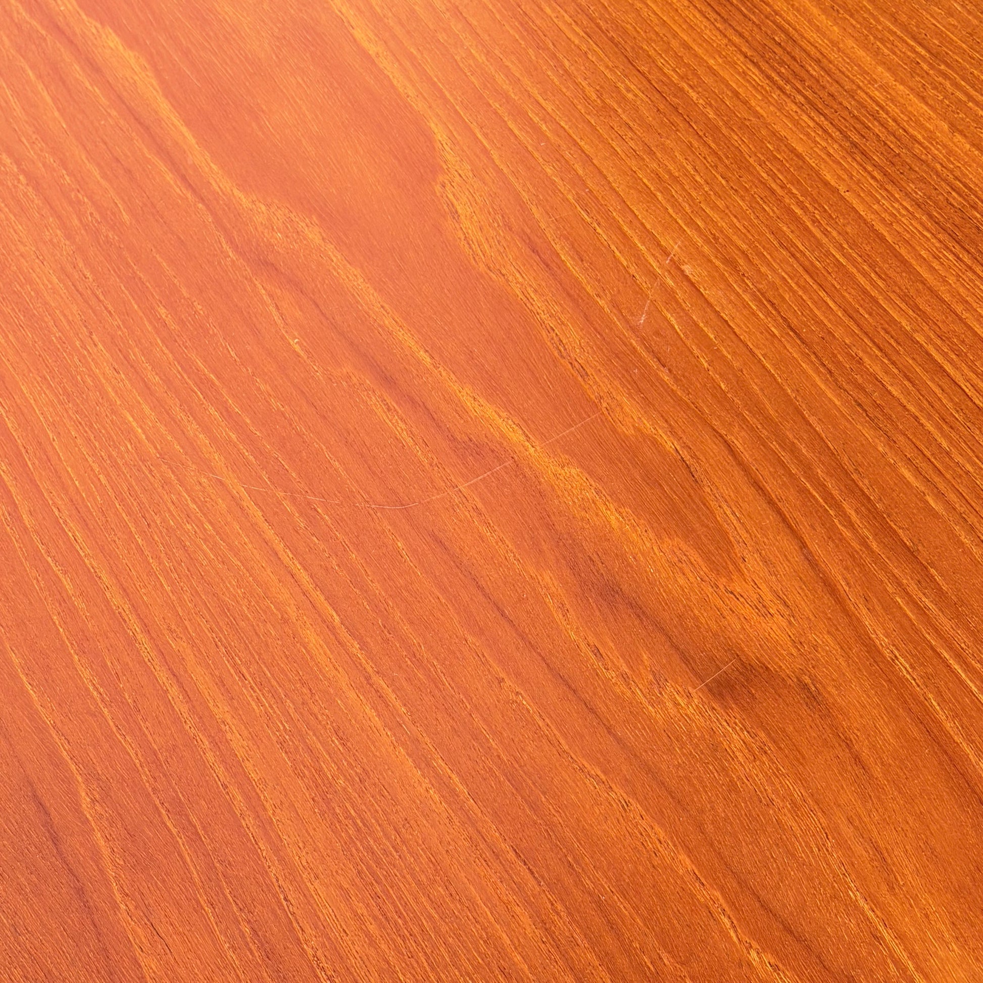 Close-up of a wooden surface with warm, orange-brown tones and natural grain, reflecting the Scandinavian-inspired design of the Vintage Parker Dining Suite 5 Piece Square - Number 140 (Refine).