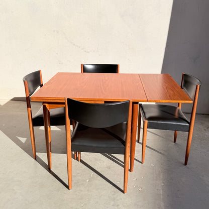 The Vintage Parker Dining Suite 5 Piece Square - Number 140 features mid-century style with a square wooden table and four black chairs, arranged on concrete flooring and illuminated by sunlight for a Scandinavian-inspired Australian look.