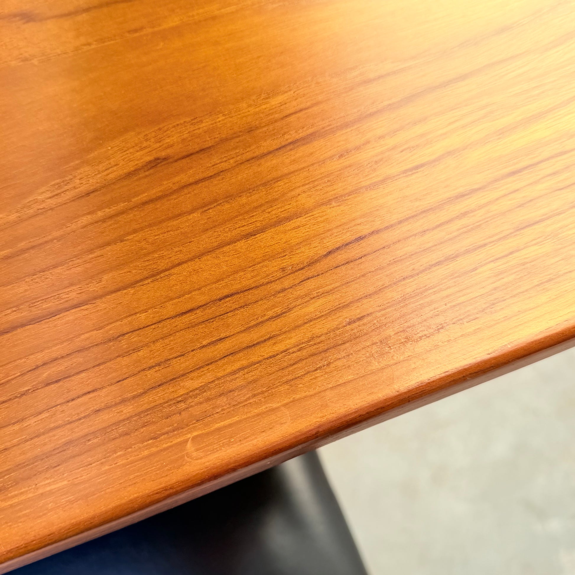 A close-up of the Vintage Parker Dining Suite 5 Piece Square - Number 140 (Refine) shows a polished wooden tabletop with smooth finish, visible grain, rounded edge, and a dark surface partially visible beneath—Scandinavian-inspired Australian design.