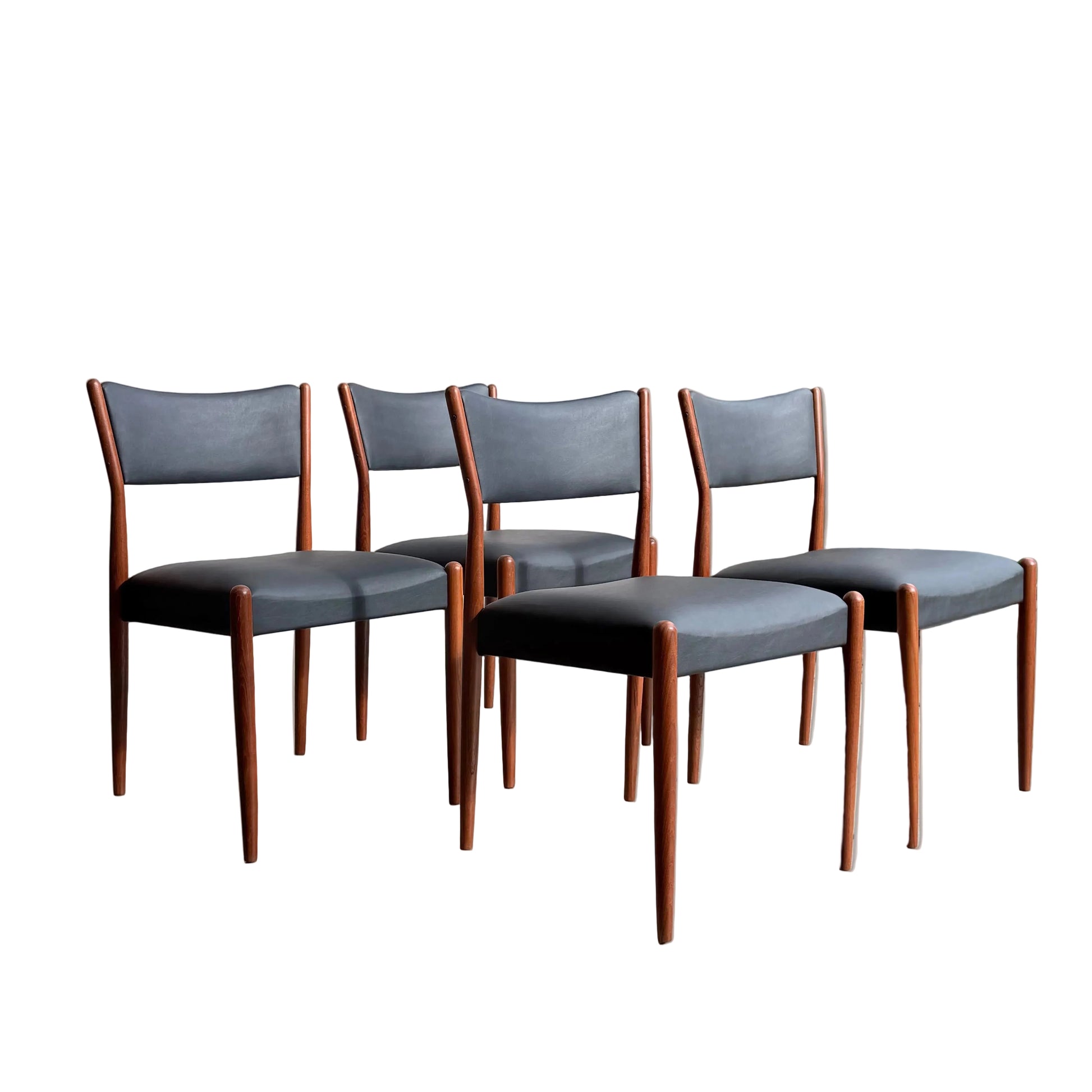Four Parker Number 97 Dining Chairs Set of 4 – Licorice Vinyl are arranged in a row in a bright, minimalist space. 