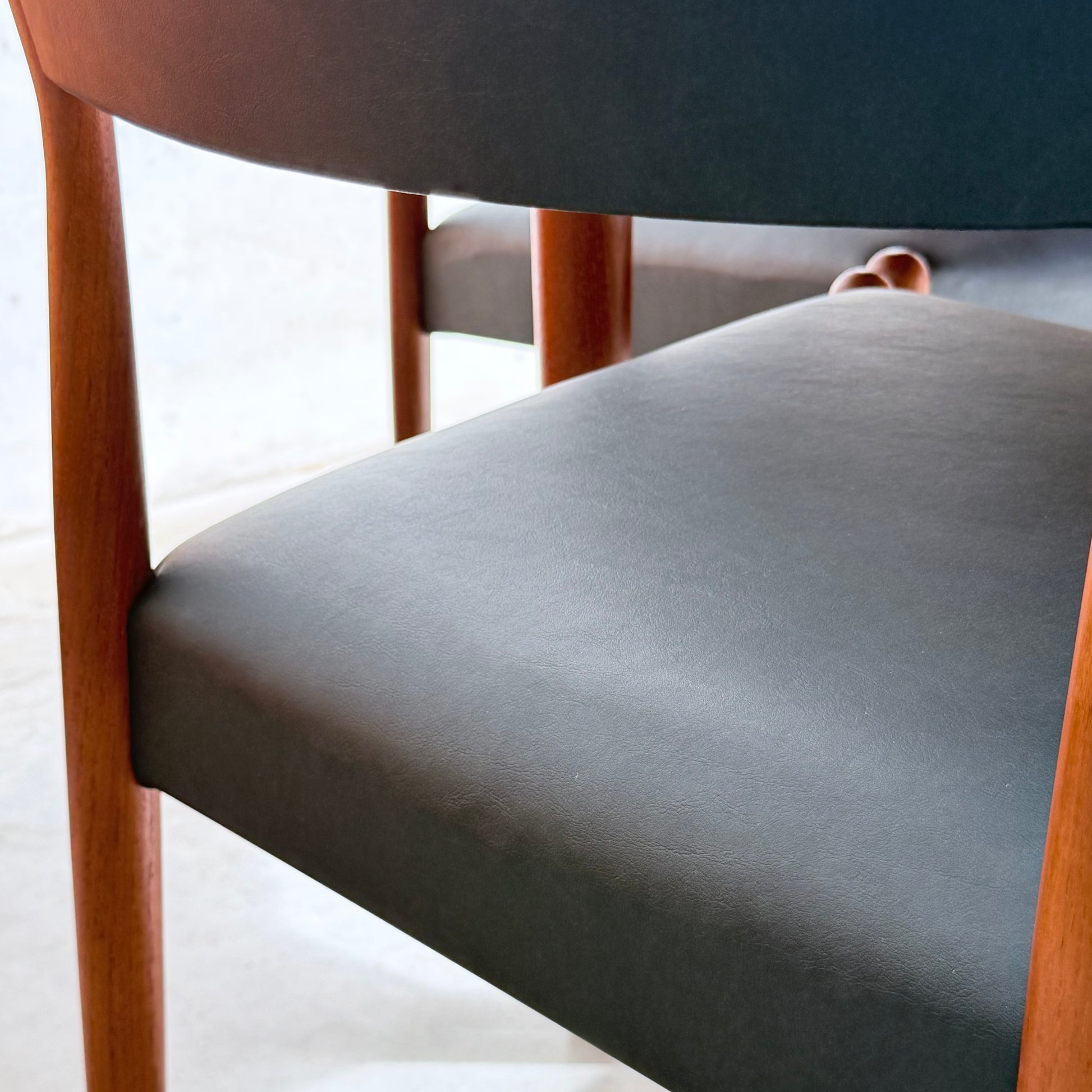 Close-up of a Parker Number 97 Dining Chair from the Set of 4 – Licorice Vinyl (Rediscover), featuring a dark upholstered seat and backrest, wooden legs and frame, and visible seat texture with classic mid-century modern design.