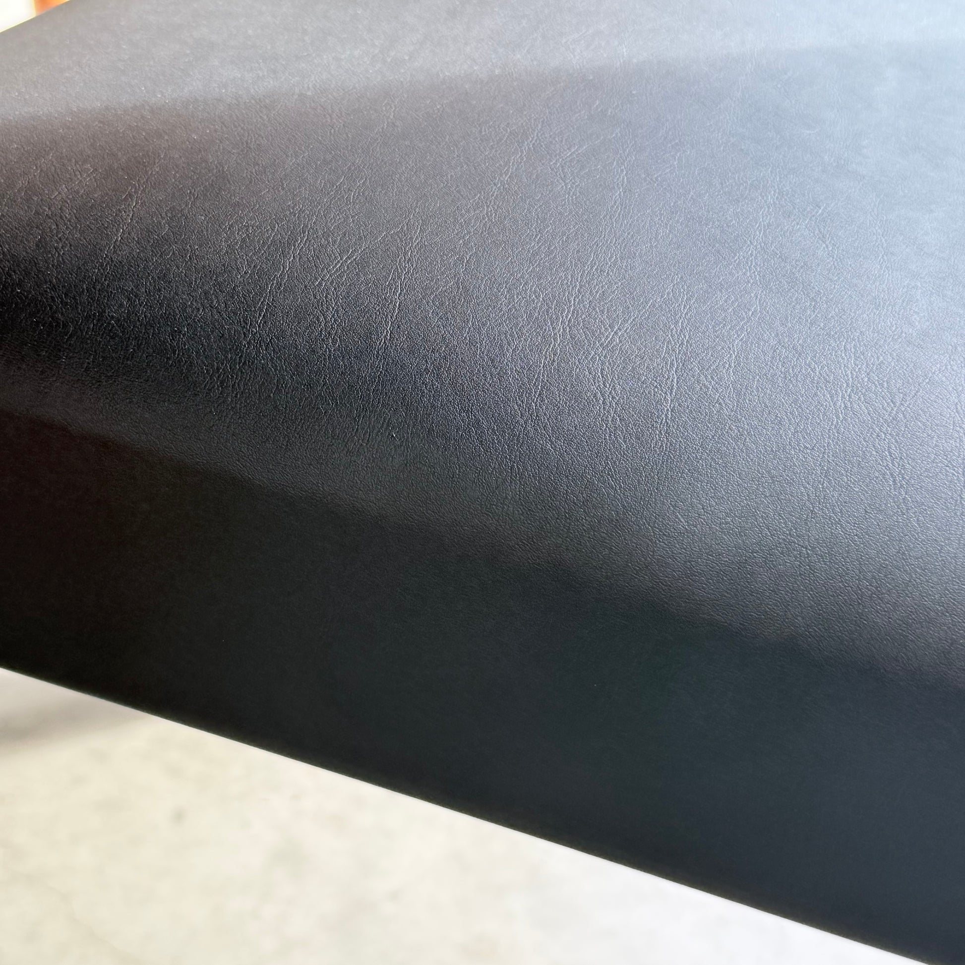 Close-up of the smooth, licorice black vinyl surface on Parker Number 97 Dining Chairs Set of 4 (Rediscover), showing subtle texture and light reflecting off the mid-century modern material.