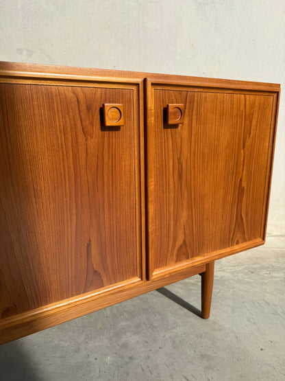A close-up of the Iconic Parker Teak 4-Door Sideboard – a restored mid century modern piece with tapered legs – showcases Australian craftsmanship, set on concrete against a plain light wall.