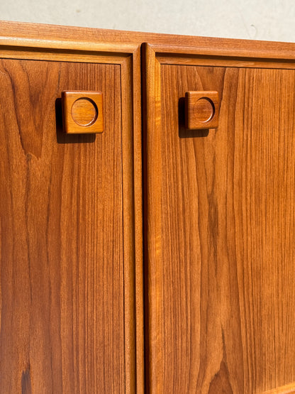 Close-up of the Iconic Parker Teak 4-Door Sideboard’s cabinet doors with square handles, highlighting natural wood grain and warm tones in bright light—a restored mid-century modern piece with tapered legs from Australia.