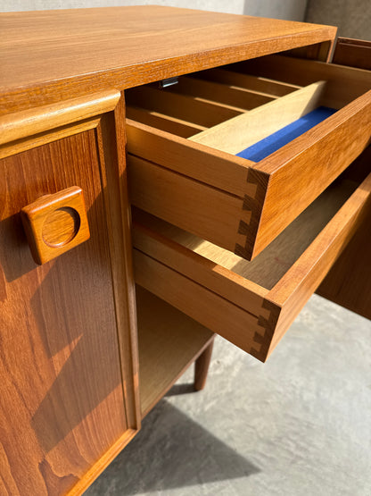 A close-up of the Iconic Parker Teak 4-Door Sideboard – Restored Mid Century Modern with Tapered Legs, showing dovetail-jointed open drawers and blue felt lining. Sunlight highlights its rich grain, sleek design, and Australian craftsmanship.