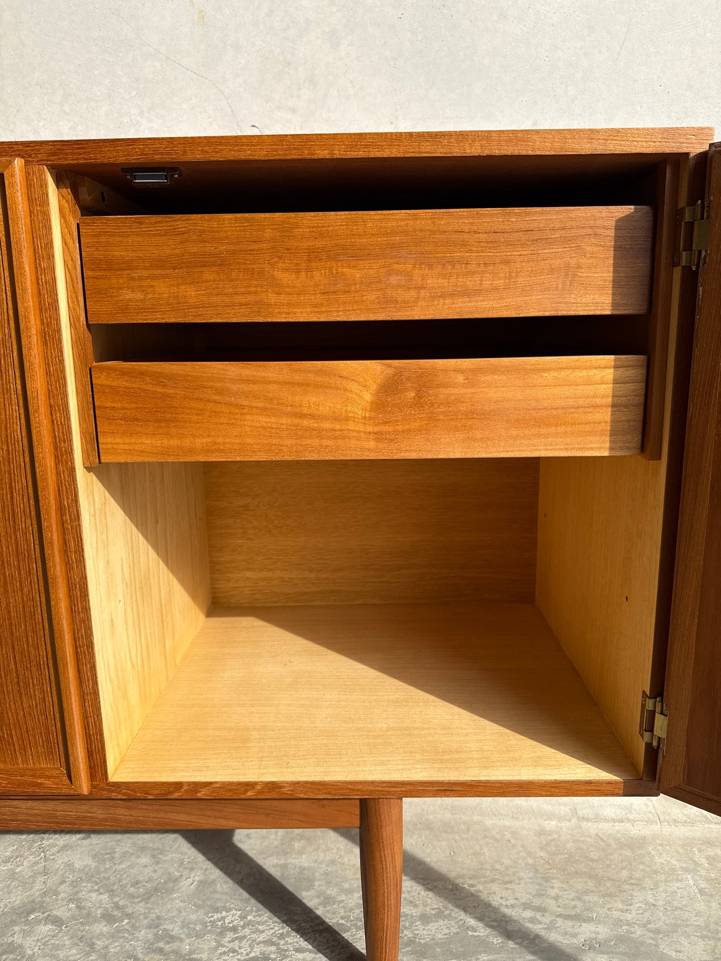 A restored Iconic Parker Teak 4-Door Sideboard (Rediscover) with tapered legs, sunlight highlighting its Australian craftsmanship, elegant wood grain, open to reveal spacious compartments and upper drawers in true mid-century modern style.