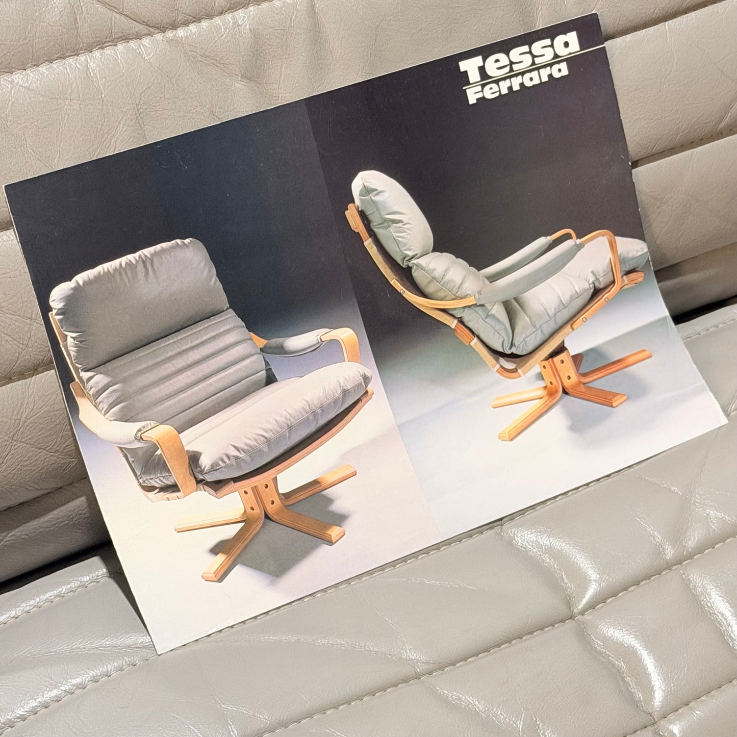 A brochure showcases two Tessa Ferrara Swivel Armchairs (Revive) with light wood frames and plush gray cushions, inspired by mid-century Australian design, set against a tufted gray leather background.