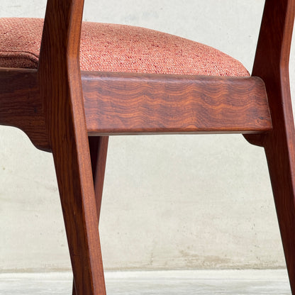 Close-up of a Vintage MCM Jens Risom Chair from a collectable set of 4, featuring angled wooden legs and a pink textured upholstered seat, inspired by classic mid-century modern design, shown against a light wall and concrete floor.