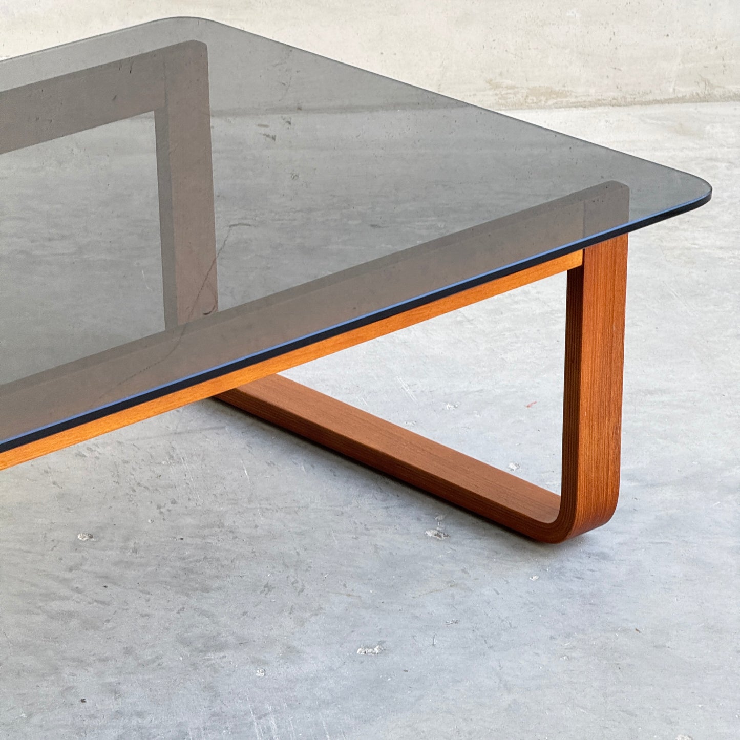The Tessa T4 - Large Coffee Table (Revive) features a rectangular smoked glass top and sleek wooden base, bringing modern minimalist style to any space.