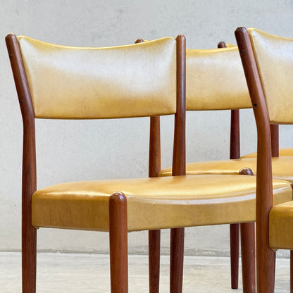 A set of six Parker Number 97 dining chairs in original mustard vinyl upholstery is arranged in a row against a light wall, showcasing their minimalist mid-century modern style that adds charm to any space.