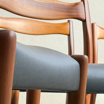 Close-up of three Fully Restored Fler 64 Dining Chairs in Liquorice Vinyl, arranged side by side against a light wall, highlighting their curved backrests and classic mid-century modern style.