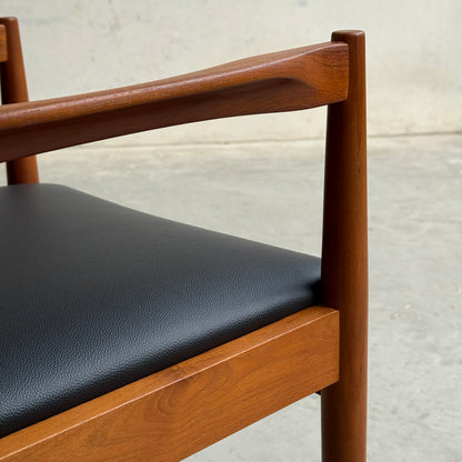 A close-up of a professionally restored Parker 89 Chair—Pre-Order: Professional Restoration of Parker 89 Chair (25% non-refundable deposit)—featuring a smooth dark brown frame and black premium vinyl seat, set against a plain wall and concrete floor.