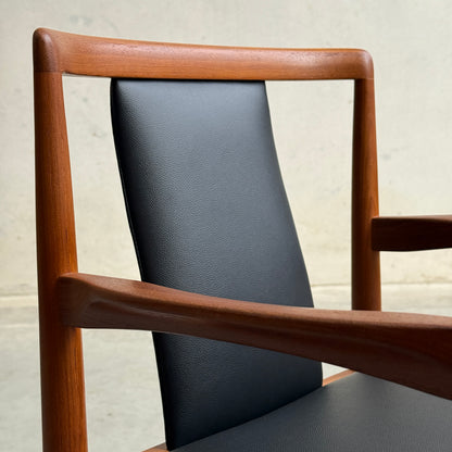 A close-up of the Pre-Order: Professional Restoration of Parker 89 Chair—pay a 25% non-refundable deposit—showing its modern wooden frame, black commercial-grade vinyl upholstery, curved armrests, and minimalist design against a light background.