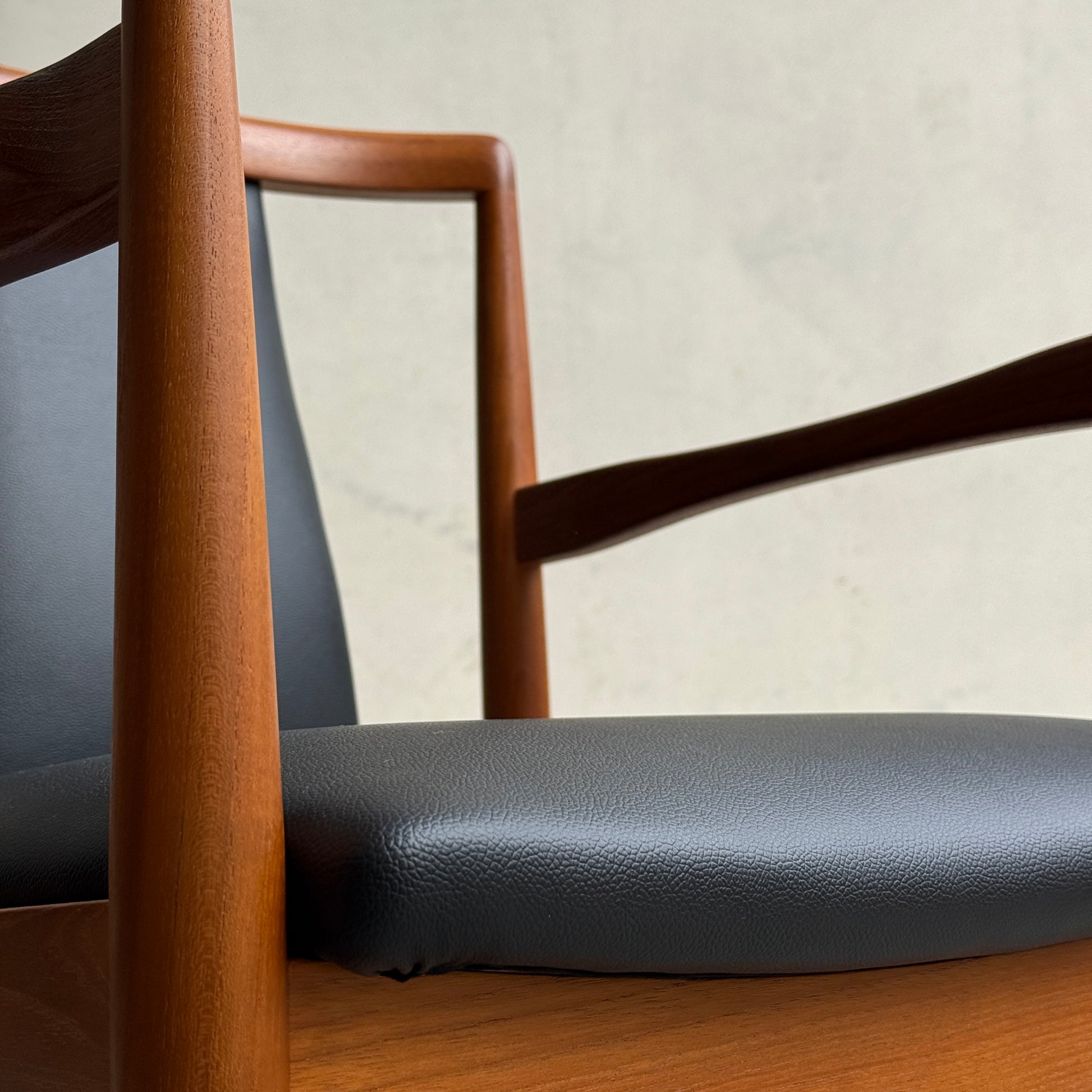 Close-up of a professionally restored Parker 89 Chair, featuring curved armrests and a black premium commercial-grade vinyl cushion. Pre-order with a 25% non-refundable deposit for minimalist style against a light background.