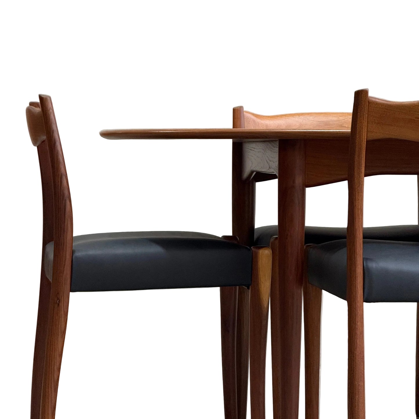 A fully restored mid-century Parker 91 oval teak dining suite with six Fler 64 blackwood chairs sits against a plain, light wall, showcasing classic Australian design.