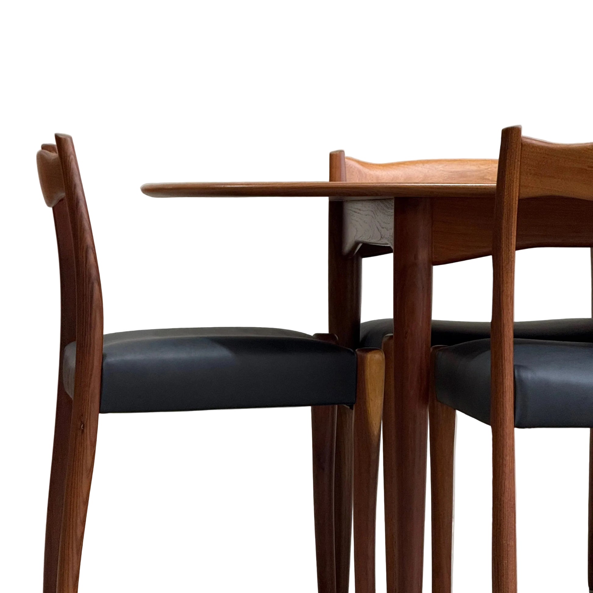 A fully restored mid-century Parker 91 oval teak dining suite with six Fler 64 blackwood chairs sits against a plain, light wall, showcasing classic Australian design.